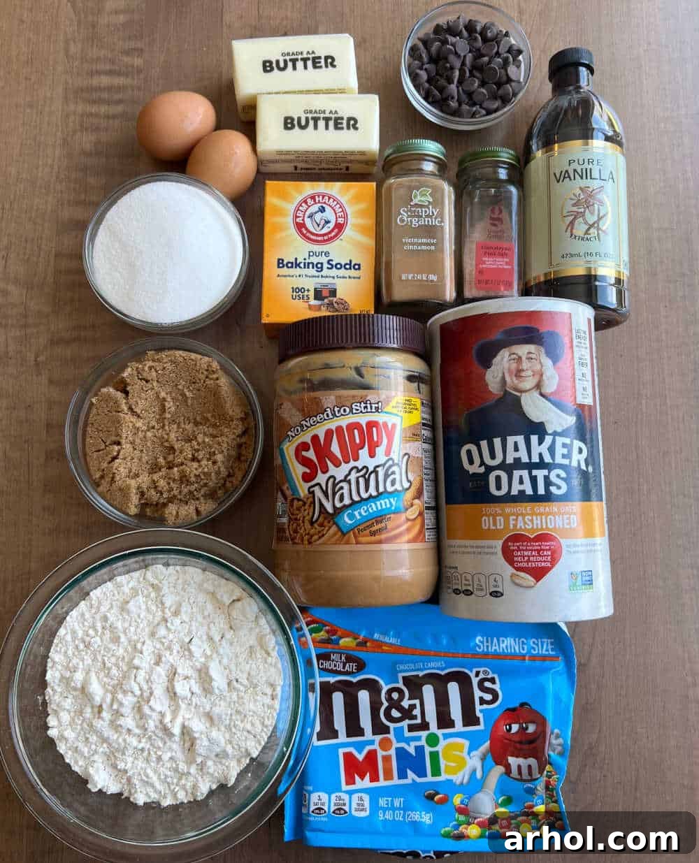 A vibrant flat lay showcasing all the essential ingredients for monster cookies: flour, oats, peanut butter, chocolate chips, and colorful candies.