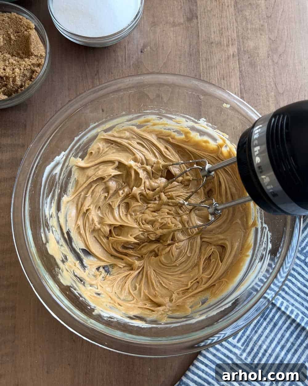 Creaming butter and peanut butter together in a mixing bowl for monster cookies.