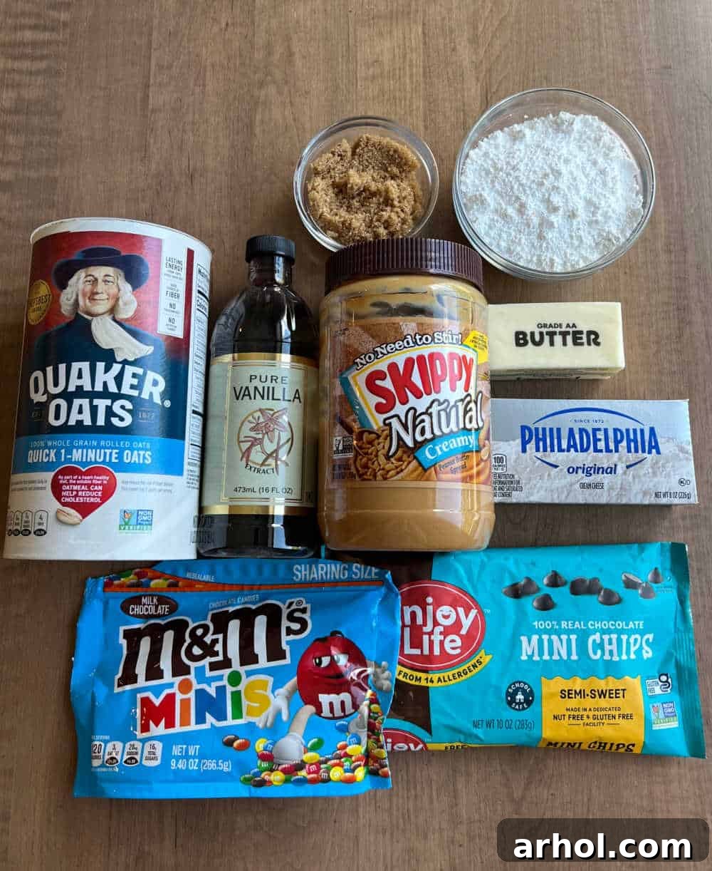 Arrangement of key ingredients for Monster Cookie Dough Dip: peanut butter, oats, vanilla extract, brown sugar, powdered sugar, butter, cream cheese, mini chocolate chips, and colorful mini M&M's.
