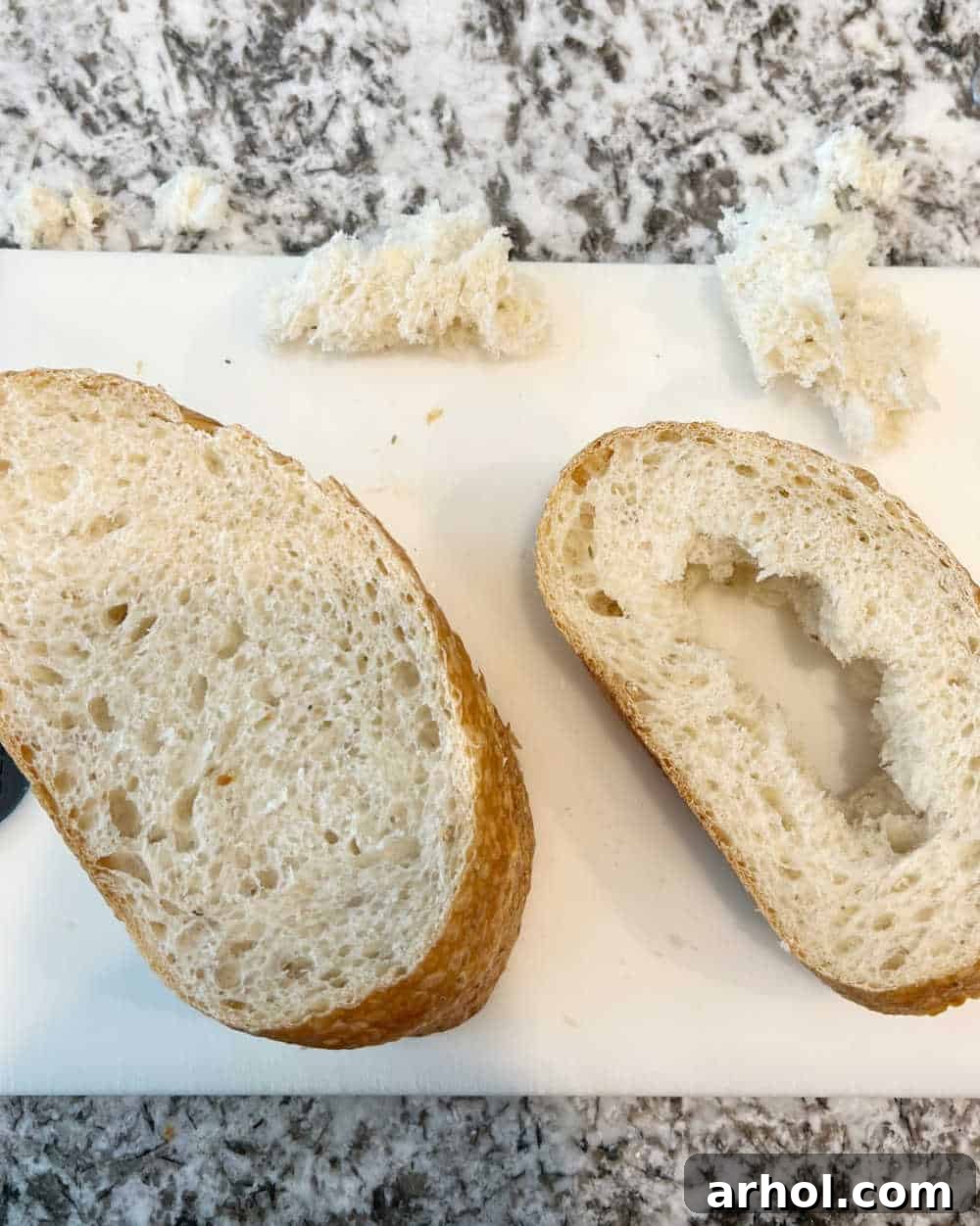Slices of thick bread with the middle torn out, creating holes for eggs, ready for cooking.