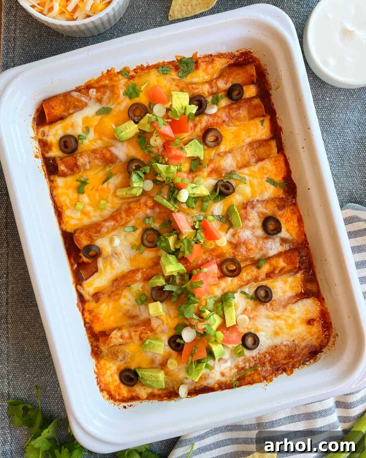 Easy ground beef enchiladas with red sauce, cheese, and fresh toppings in a white casserole dish, ready to be served.