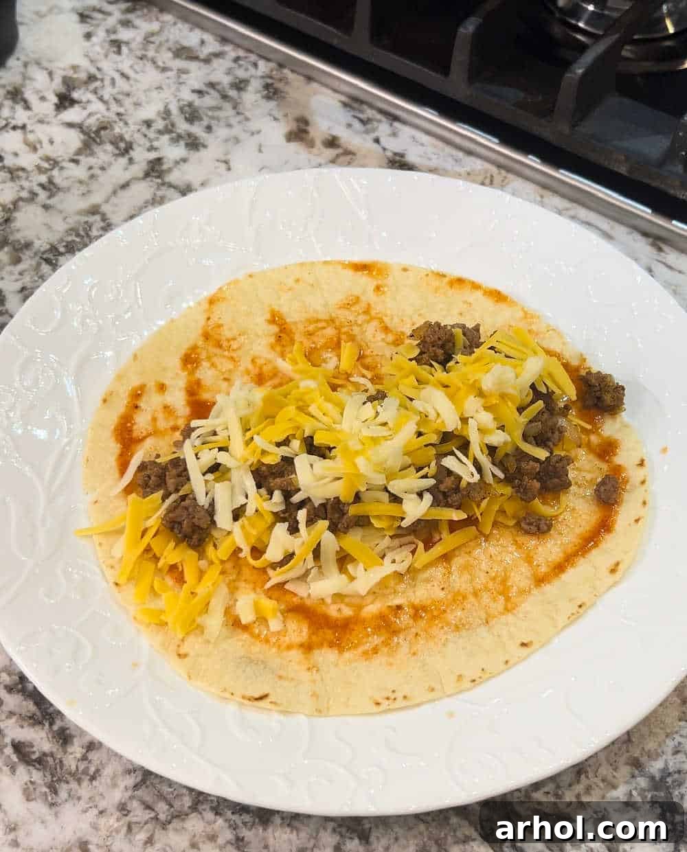 Filling flour tortillas with seasoned ground beef and shredded cheese.