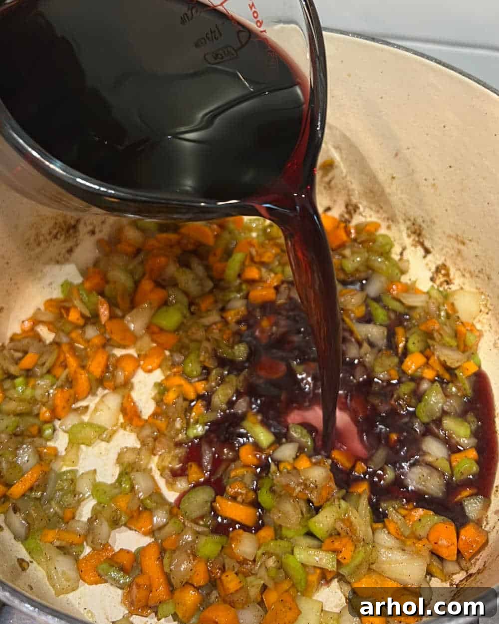 Melt-In-Your-Mouth Braised Short Ribs 5 pour wine over vegetables in dutch oven.
