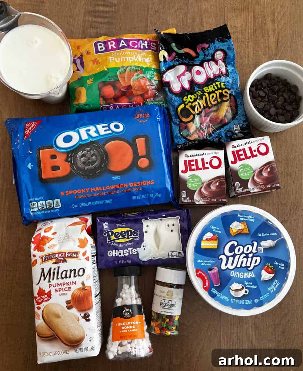 Quick Spooky Dirt Cups 3 A vibrant display of Halloween dirt cup ingredients including Halloween Oreos, instant pudding, Cool Whip, Milano cookies, milk, and various themed candies.
