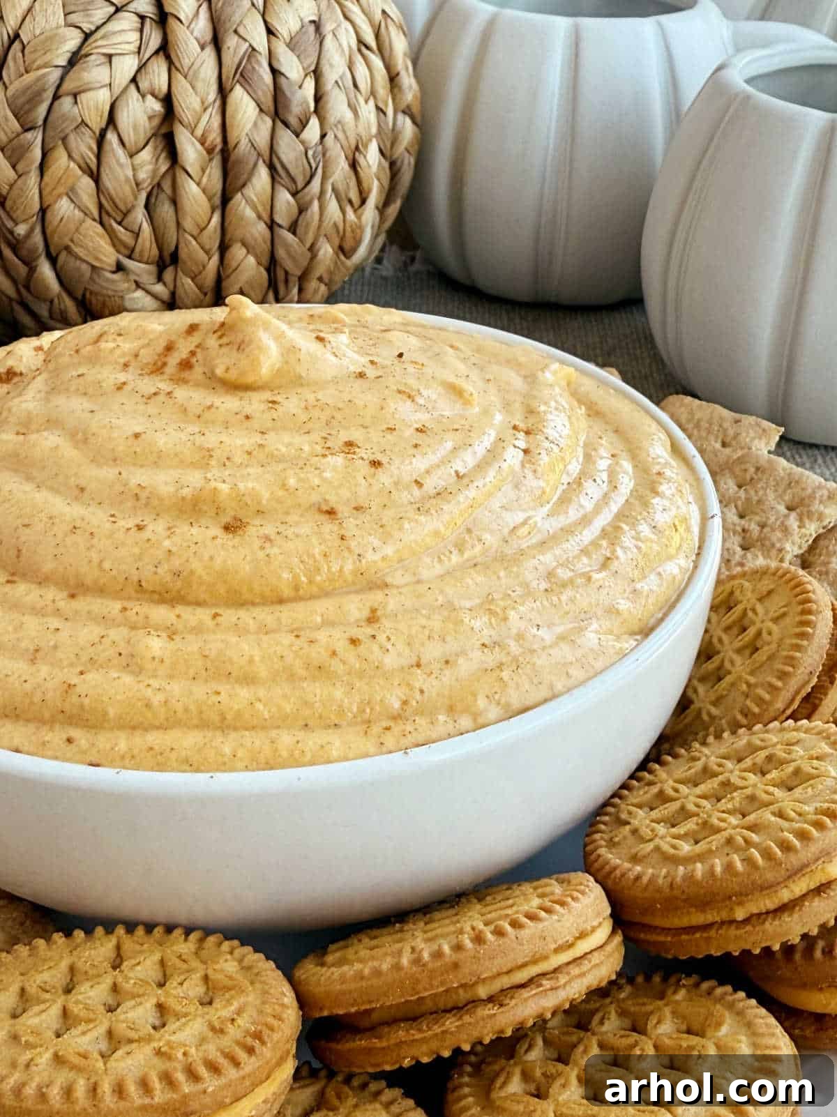 Delicious pumpkin cream cheese dip served in a festive bowl with various dippers like cookies and graham crackers.