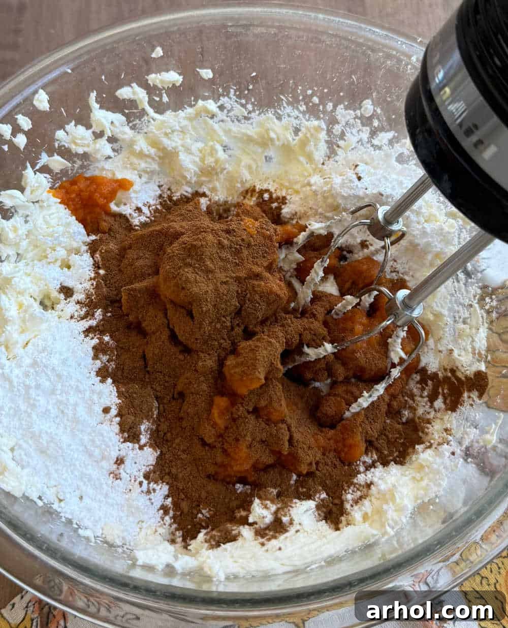 Mixing pumpkin puree, powdered sugar, and spices into the cream cheese base.