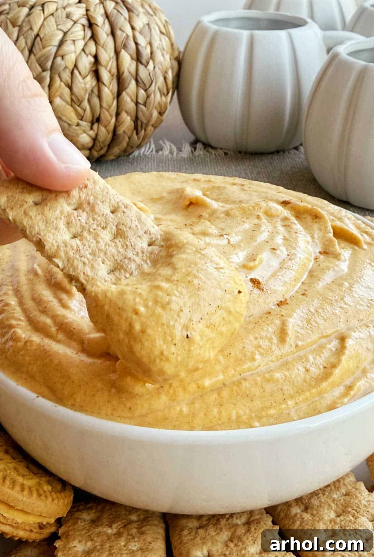 Close-up of pumpkin cheesecake dip generously spread on a graham cracker, ready to eat.