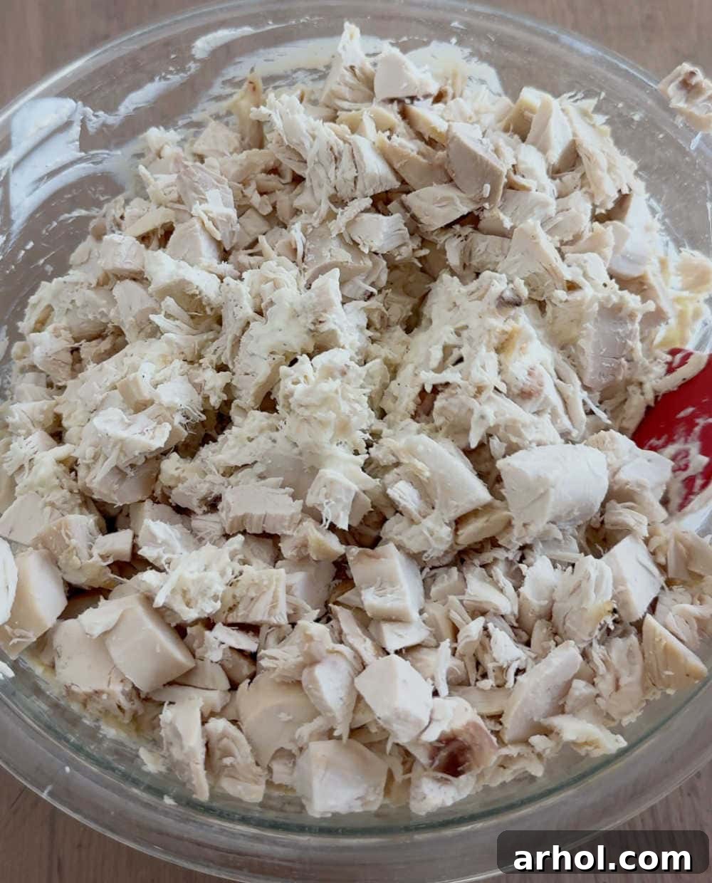 Stirring cooked chicken pieces into the creamy casserole sauce mixture.