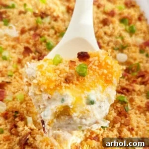 A serving spoon lifting a portion of Million Dollar Chicken Casserole.