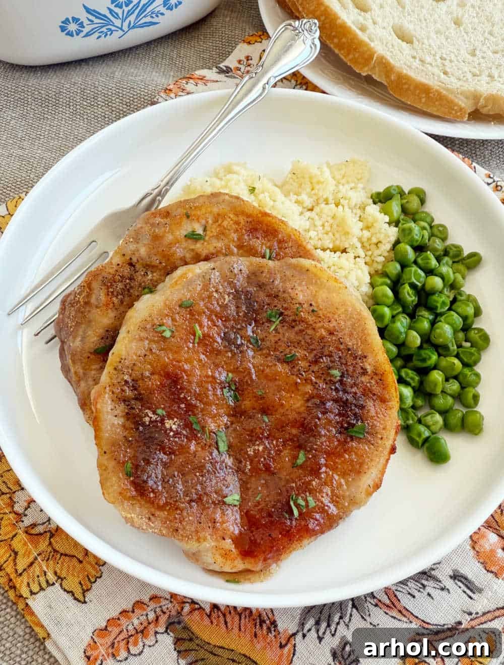 Brown Sugar Glazed Baked Pork Chops 8 A single baked pork chop, richly coated in brown sugar and paprika glaze, garnished with fresh herbs and served on a plate.