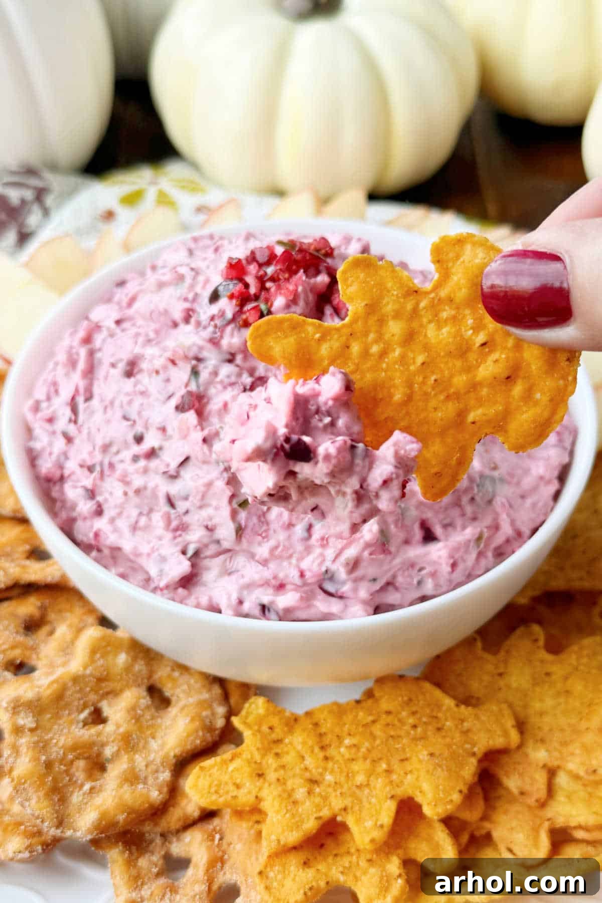 cranberry jalapeno cream cheese dip on leaf shaped tortilla chip.