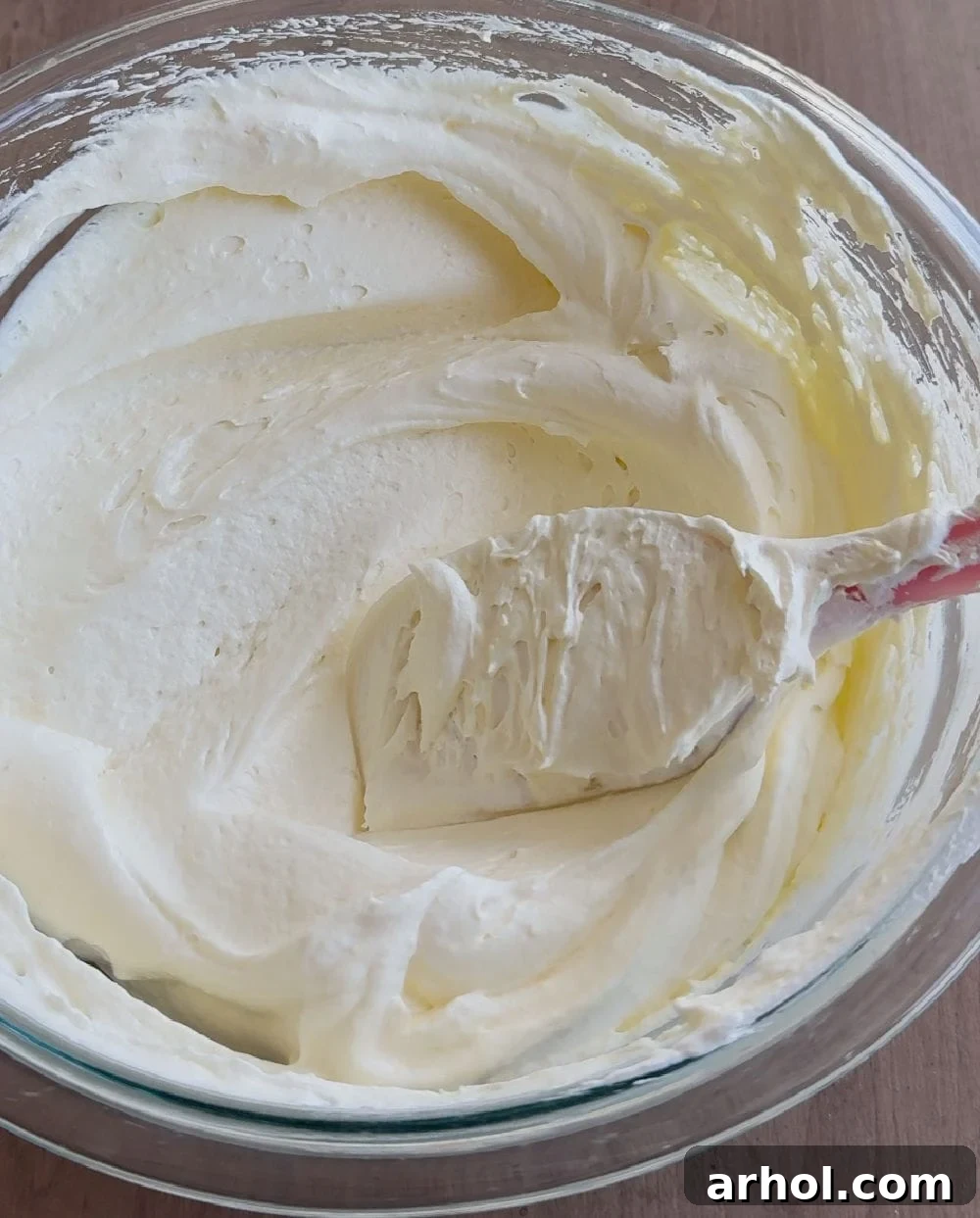 A spatula gently folds whipped topping into the creamy pudding mixture, ensuring a light and airy consistency for the dip.