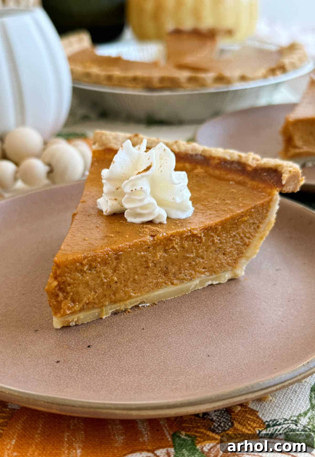 A perfectly baked slice of easy pumpkin pie, topped with a generous dollop of whipped cream and a sprinkle of cinnamon, resting on a white plate with a fork.