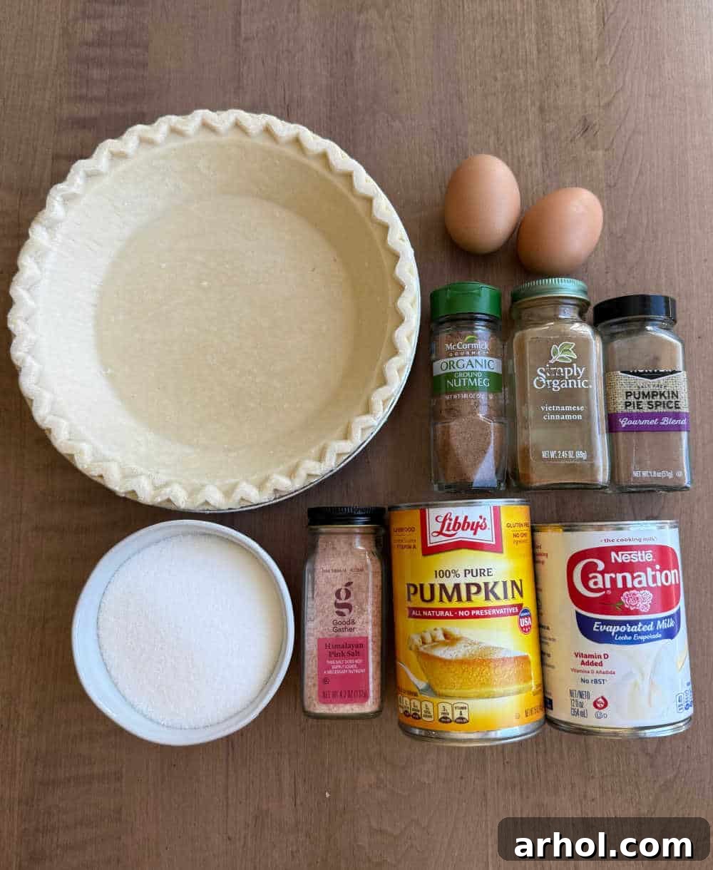 Canned pumpkin puree, eggs, evaporated milk, sugar, and various spices laid out on a kitchen counter, ready for mixing into pumpkin pie filling.