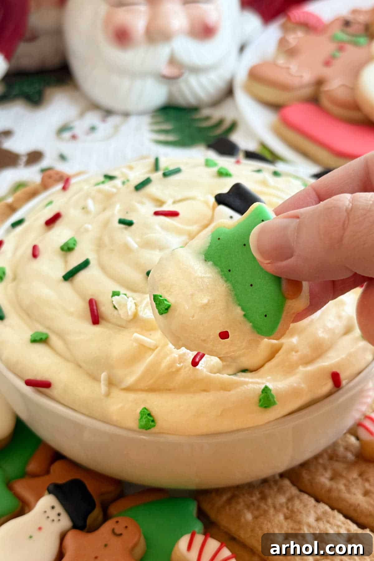 Dreamy Christmas Sugar Cookie Dip 8 dipping sugar cookies into a bowl of Christmas sugar cookie dip.