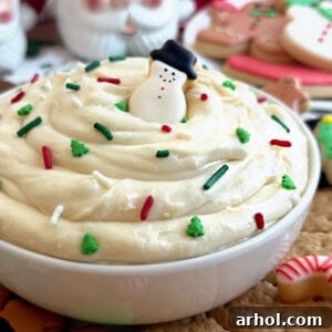 Dreamy Christmas Sugar Cookie Dip 9 Christmas sugar cookie dip with snowman cookie in white bowl, adorned with holiday sprinkles.