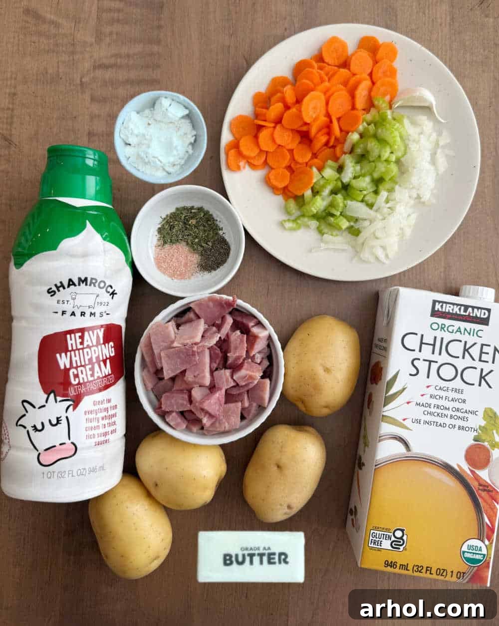 Ingredients for ham and potato soup laid out: diced ham, Yukon Gold potatoes, chicken broth, carrots, celery, onion, garlic, and heavy cream.