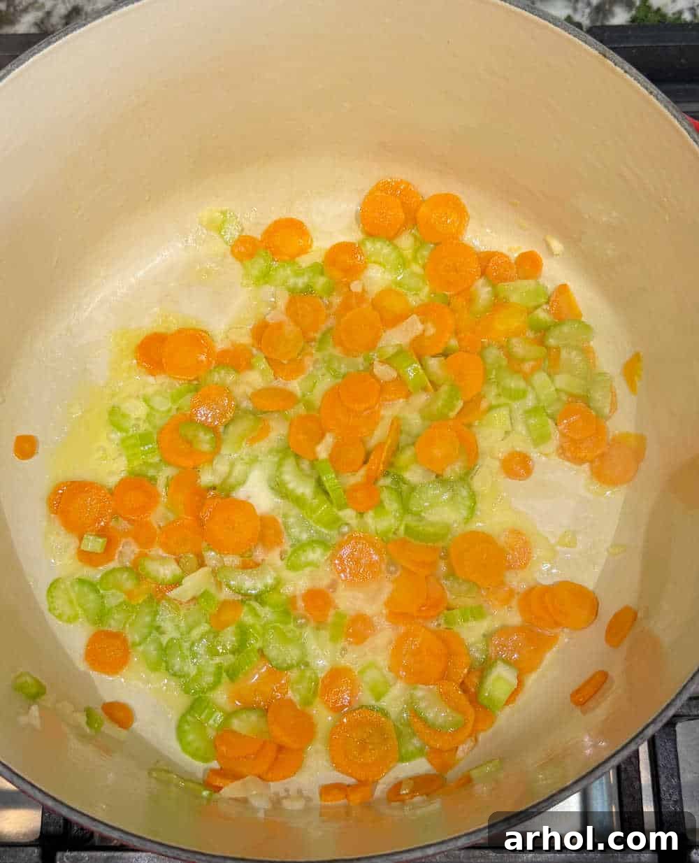 Sautéing diced onions, celery, and carrots in melted butter in a Dutch oven.