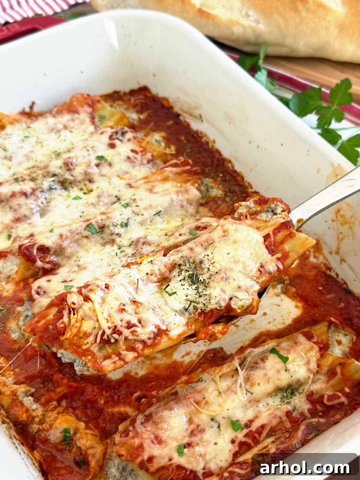 Manicotti with meat on a serving spoon, highlighting the rich filling and sauce.