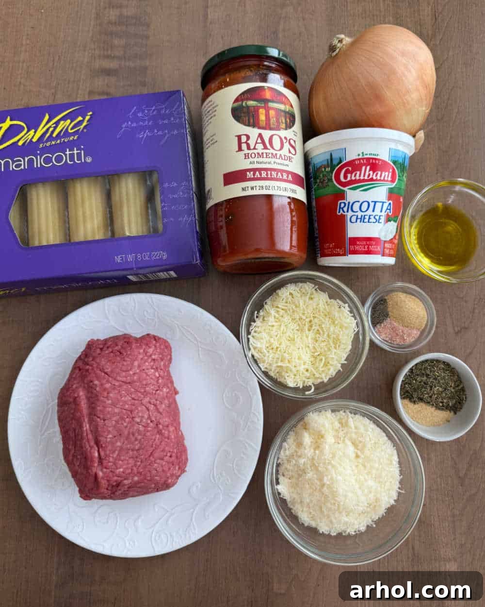 Ground beef, uncooked manicotti shells, various cheeses, onion, and seasonings displayed as ingredients.