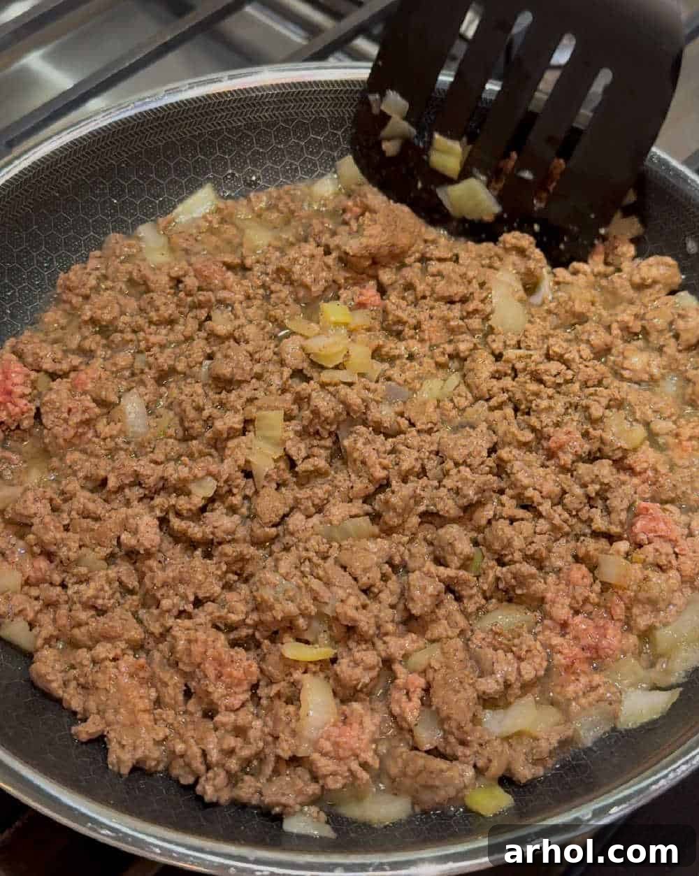Browning ground beef with diced onions in a large skillet, forming the flavorful base.