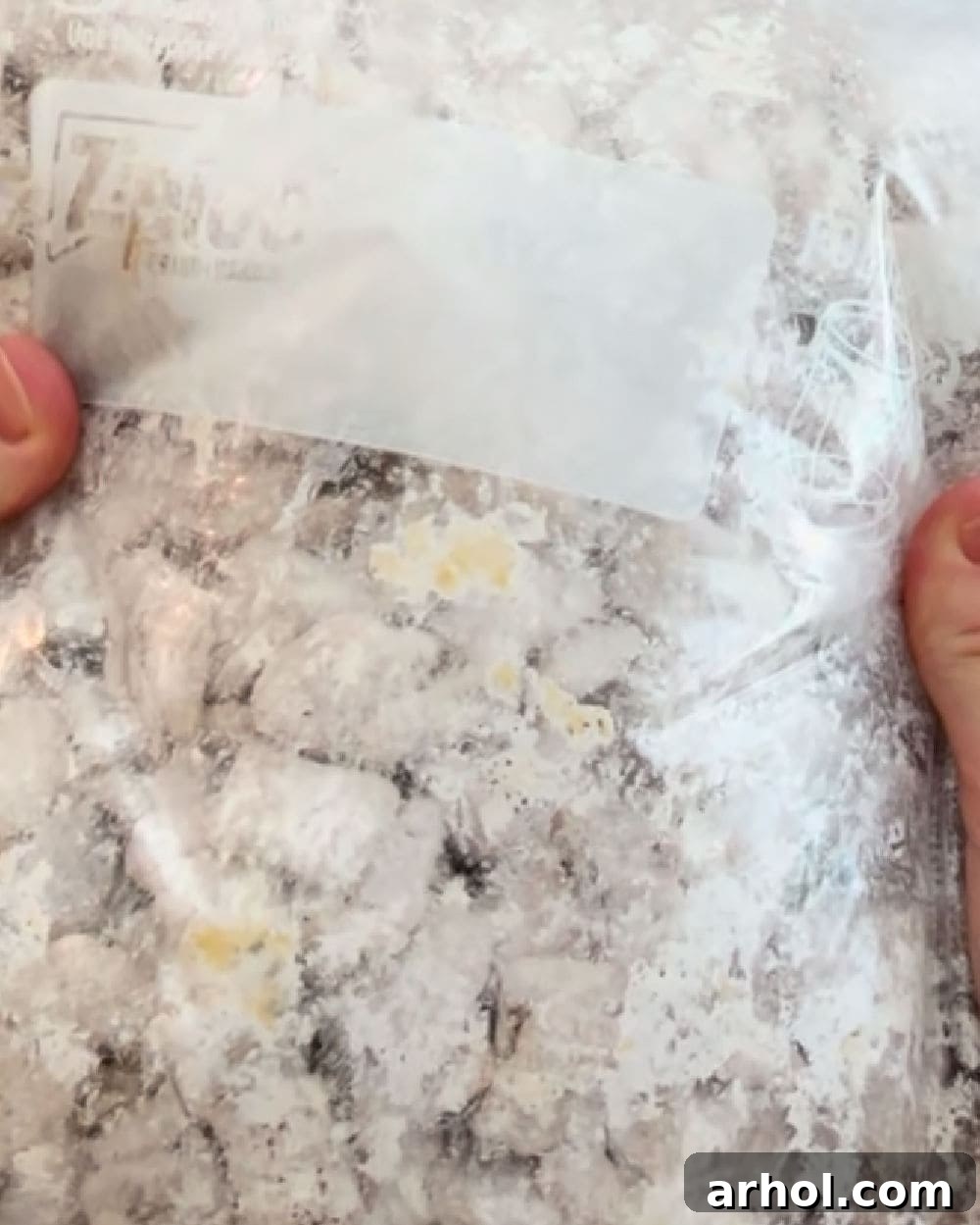 A large freezer bag being shaken to coat the chocolate-covered Chex cereal with powdered sugar.