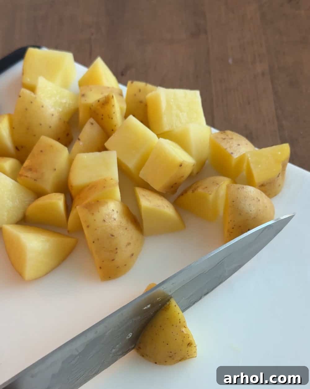Clean Yukon Gold potatoes precisely cut into bite-sized pieces on a cutting board, ready for cooking.