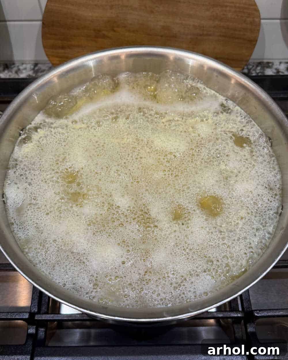 A large pot of cut potatoes gently simmering on the stove, surrounded by bubbling water.