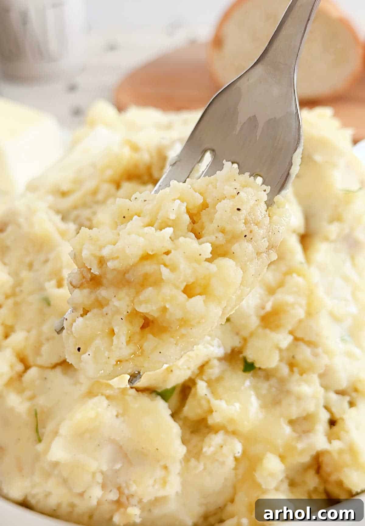 A fork piercing into a generous scoop of rustic skin-on mashed potatoes, highlighting their tender texture and visible potato skins.