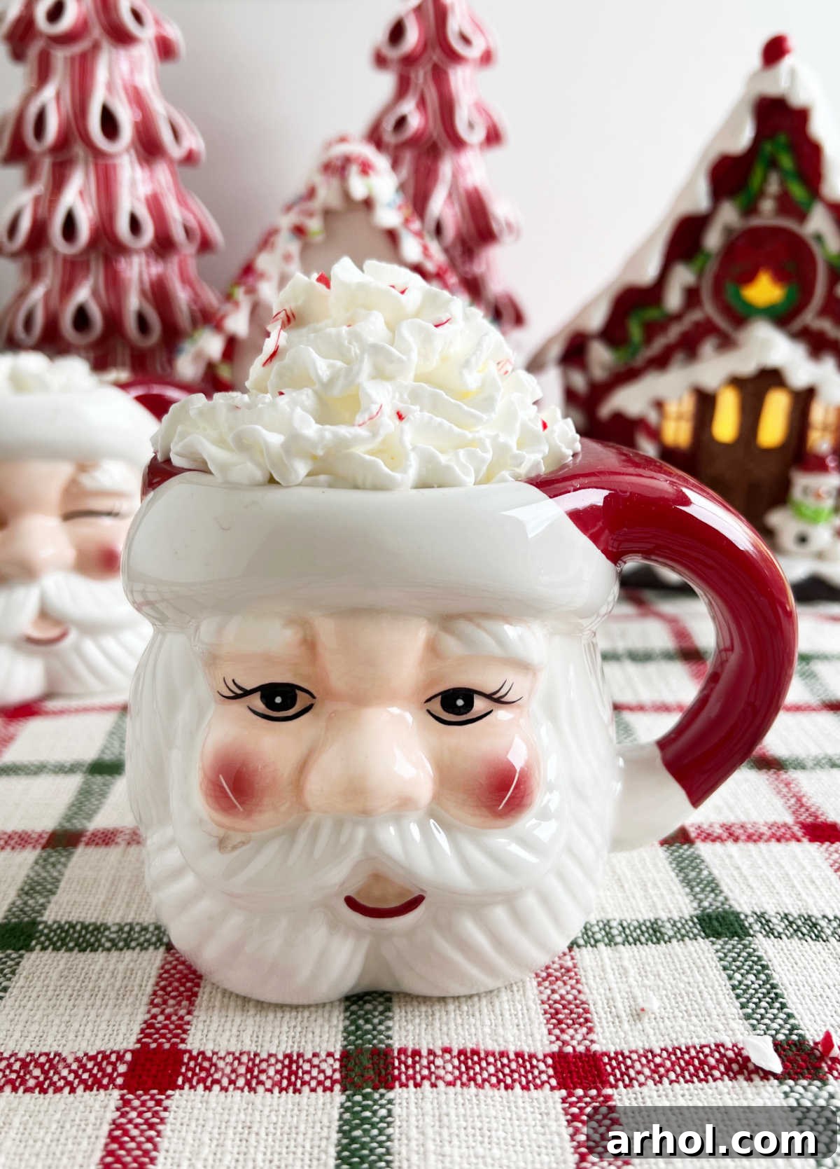 Ultimate Peppermint Hot Chocolate 2 A festive Santa mug filled with homemade peppermint hot cocoa, topped with whipped cream and crushed peppermint candies, resting on a wooden table, evoking holiday cheer.