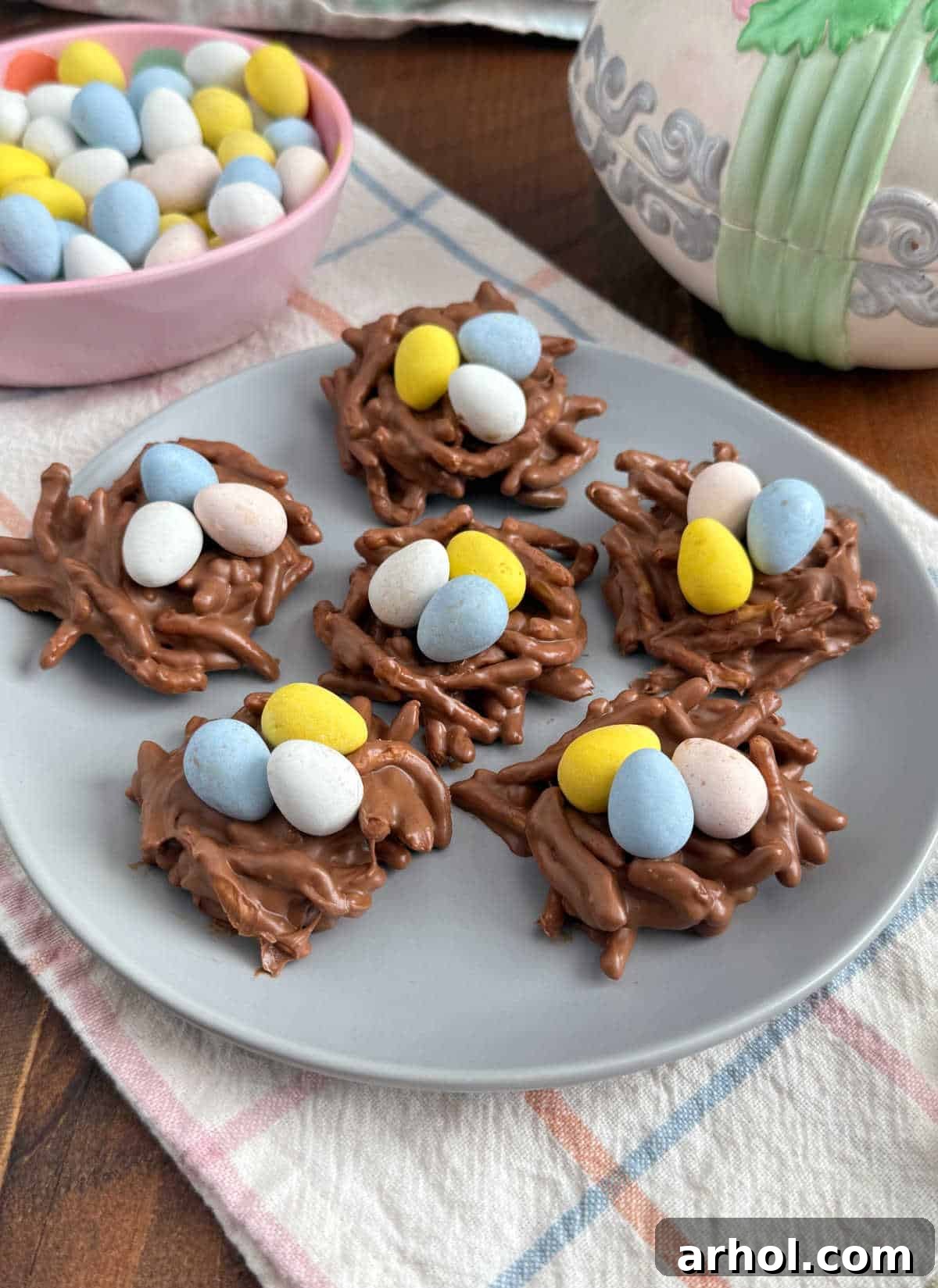 Easter bird's nest cookies featuring crunchy chow mein noodles, rich chocolate, and colorful candy eggs on a blue plate.
