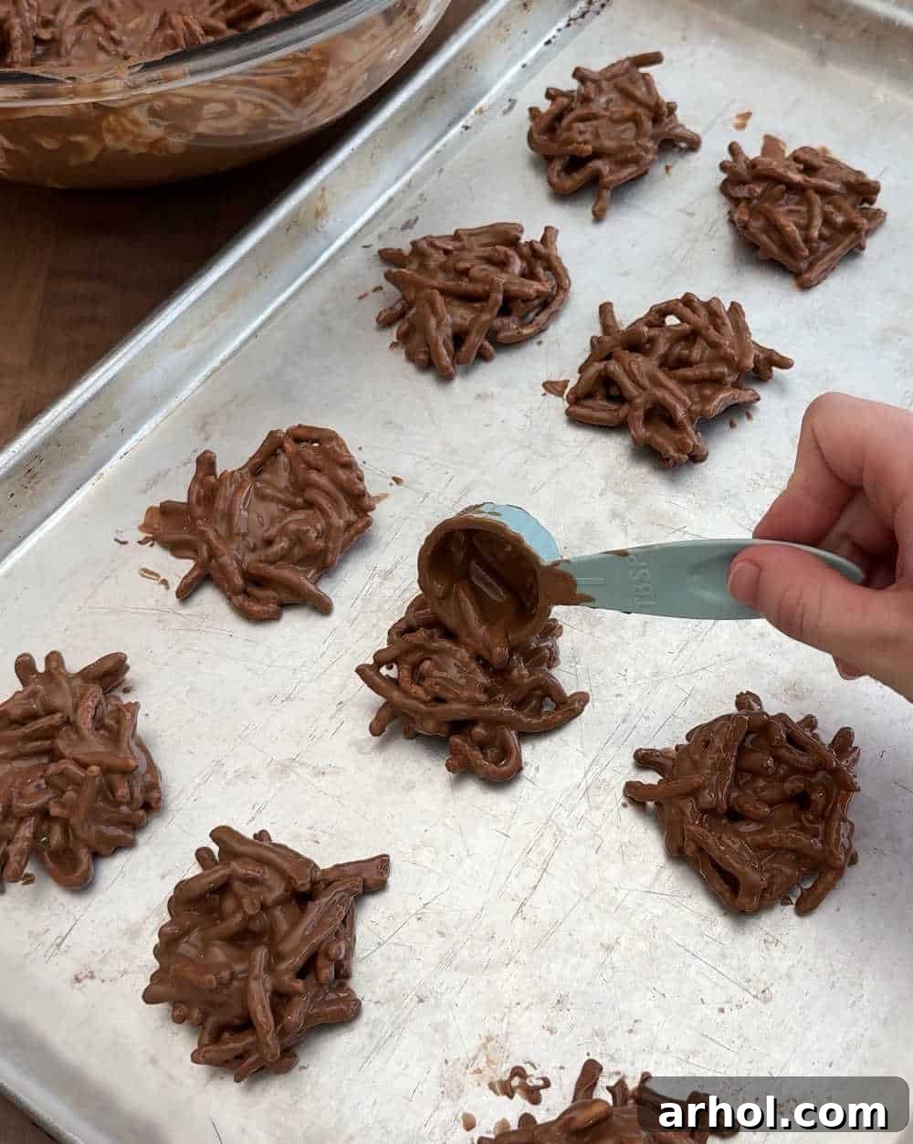 Scooping and shaping individual bird's nest cookies onto a parchment-lined baking sheet.