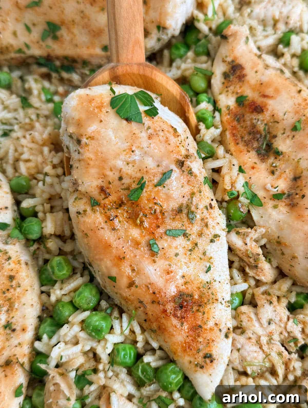 Golden-brown chicken breast with fluffy rice and green peas, served on a spoon.