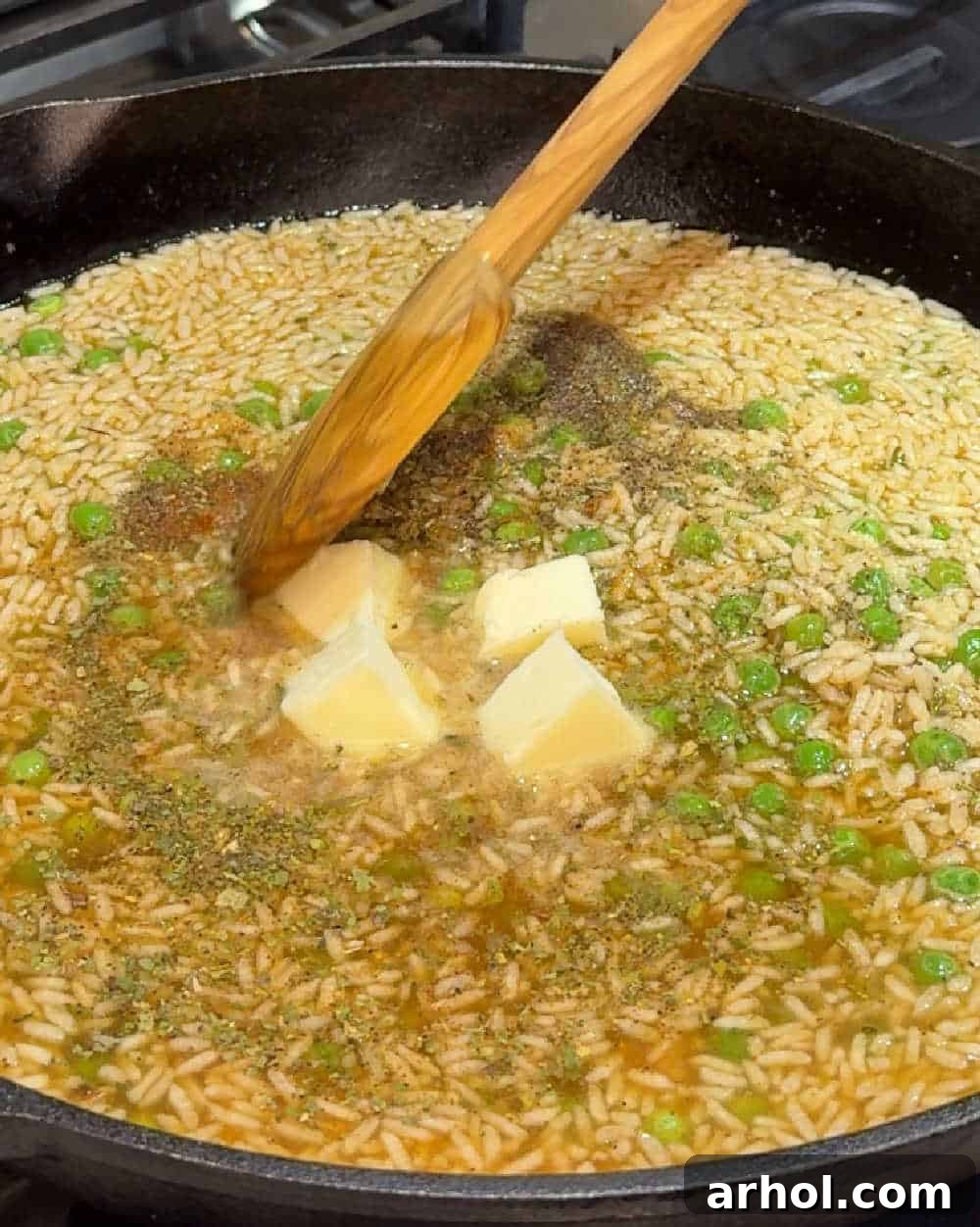 Stirring butter and spices into the rice and pea mixture in a pan.