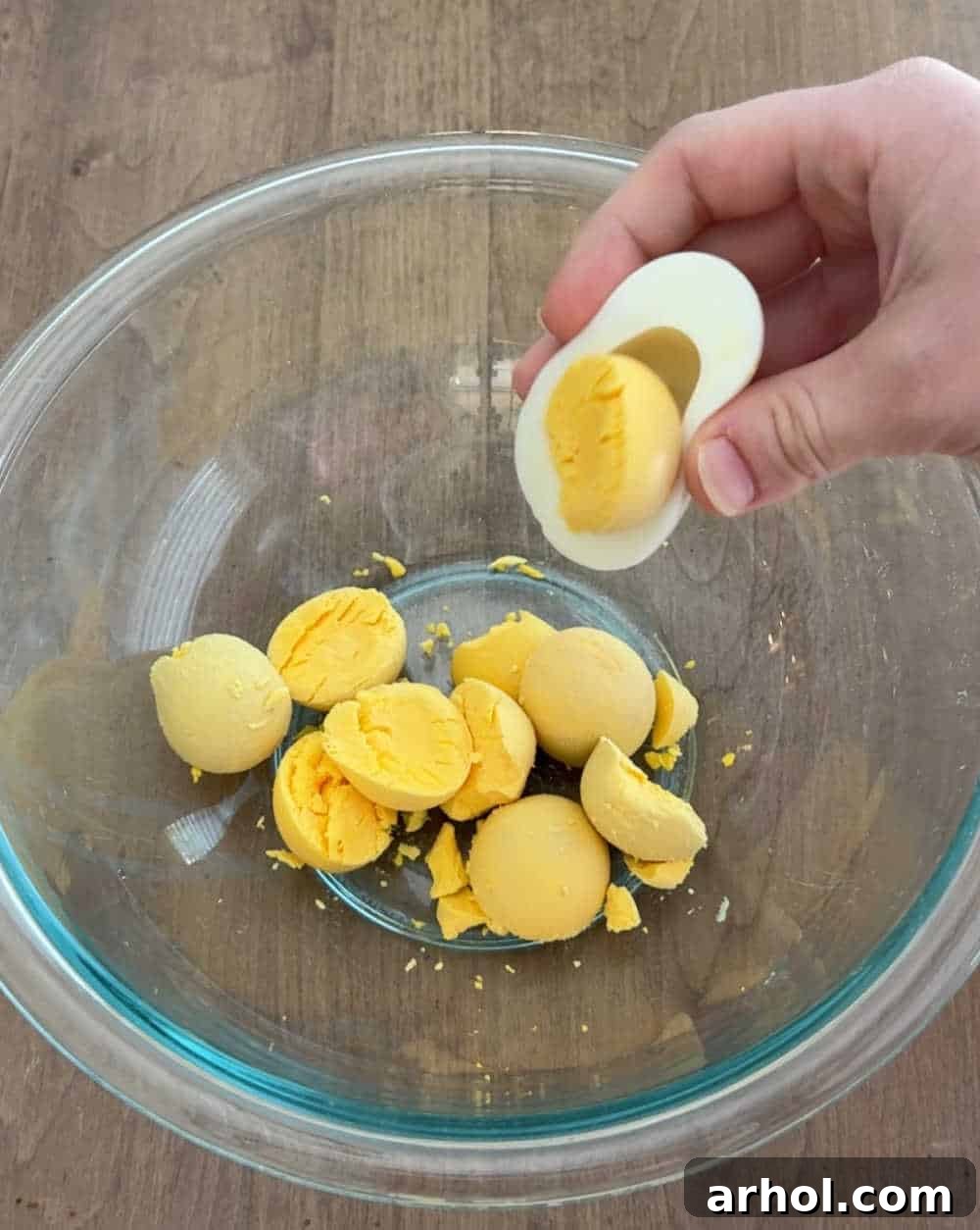 Hard-cooked egg yolks scooped into a white mixing bowl, ready for mashing and mixing.