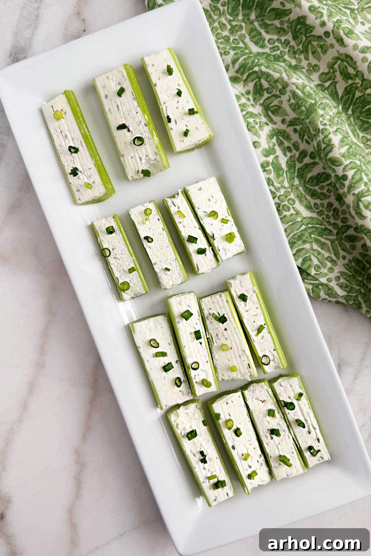 Crisp celery stalks generously stuffed with creamy, seasoned cream cheese and garnished with fresh chives, ready to serve as a delightful appetizer.