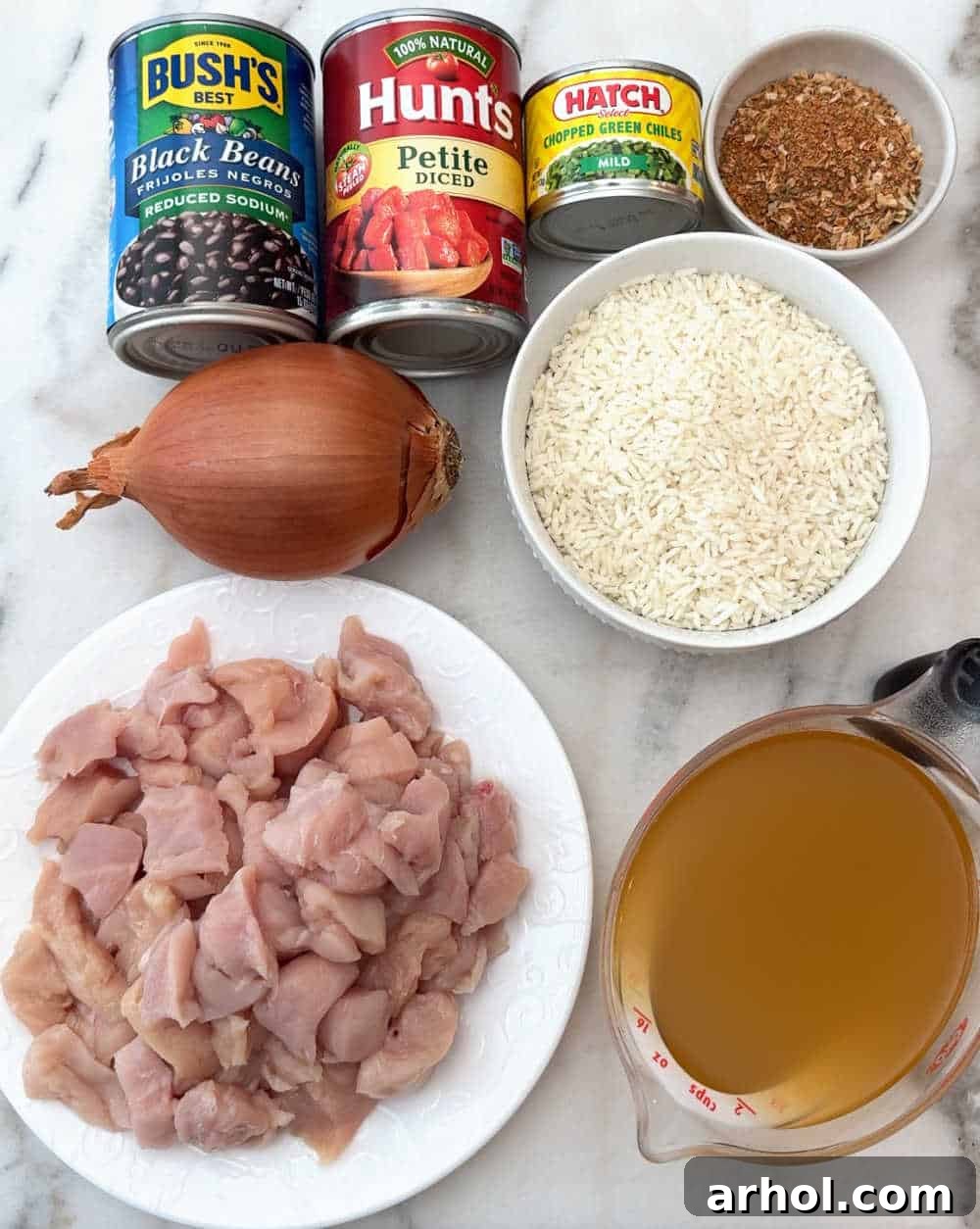 Key ingredients for One-Pan Mexican Chicken and Rice: chicken, broth, onion, rice, canned black beans, diced tomatoes, green chiles, and taco seasoning.