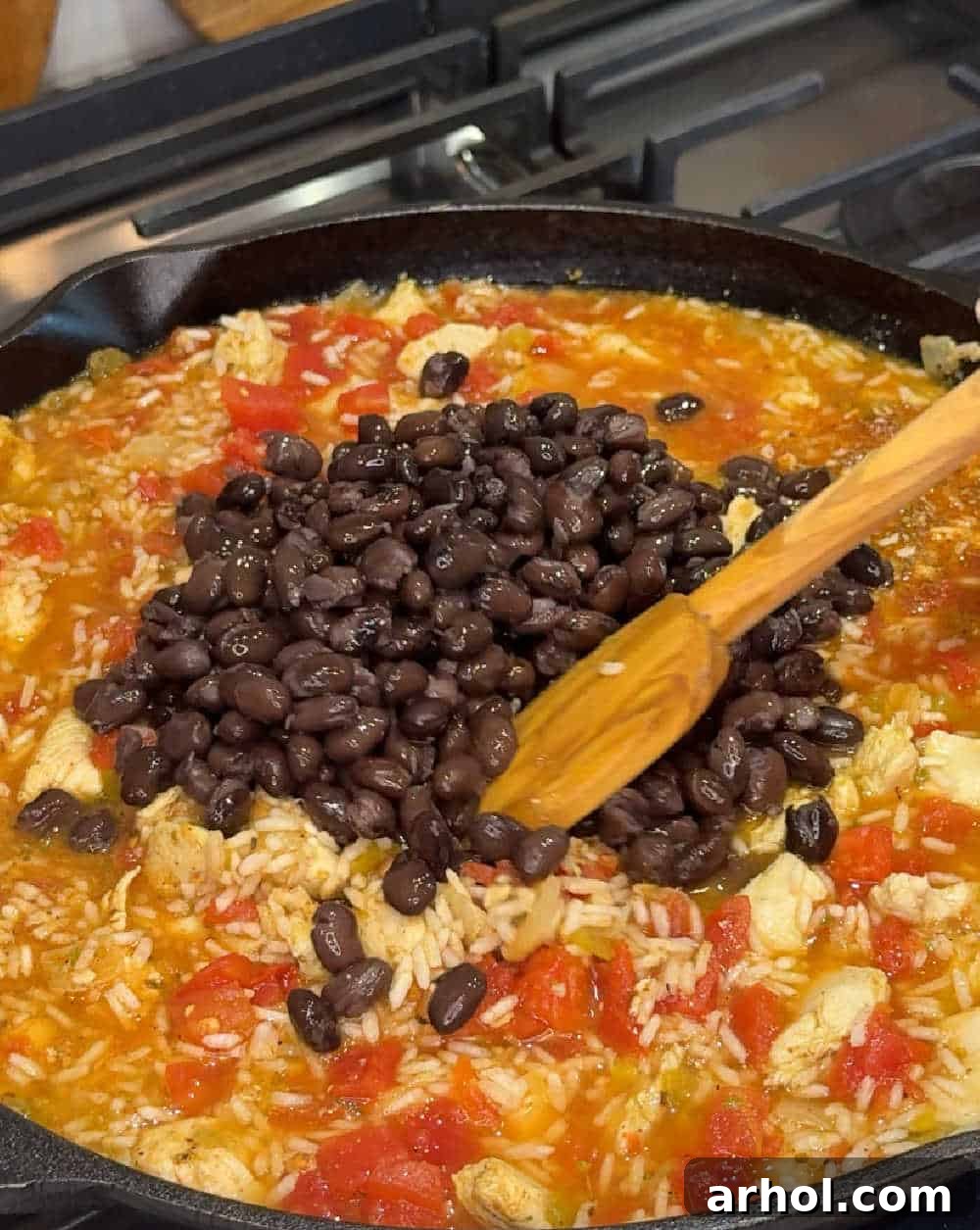 Adding black beans and diced tomatoes to the skillet.