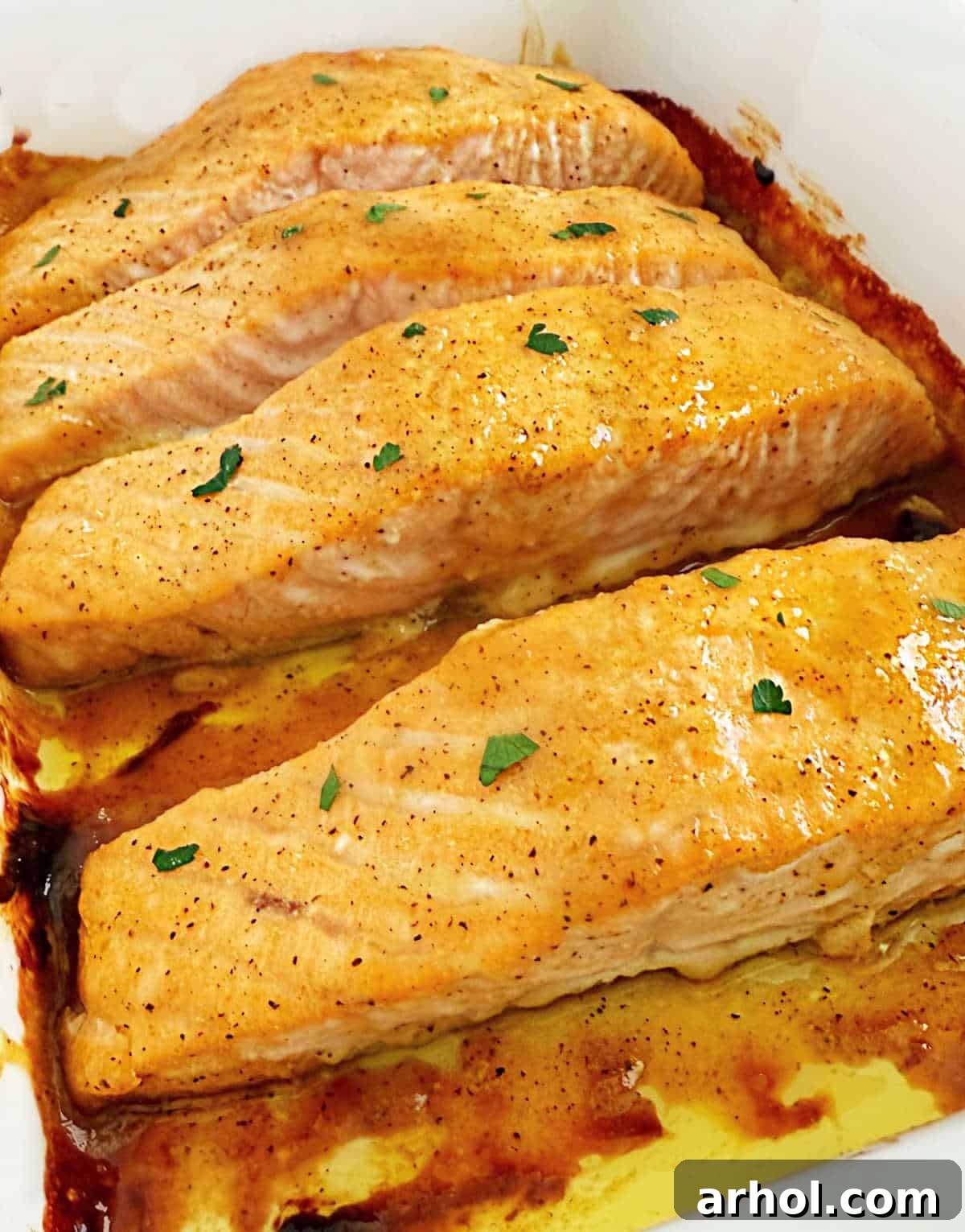 Golden Baked Honey Mustard Salmon 2 baked honey mustard salmon fillets with parsley in casserole dish.
