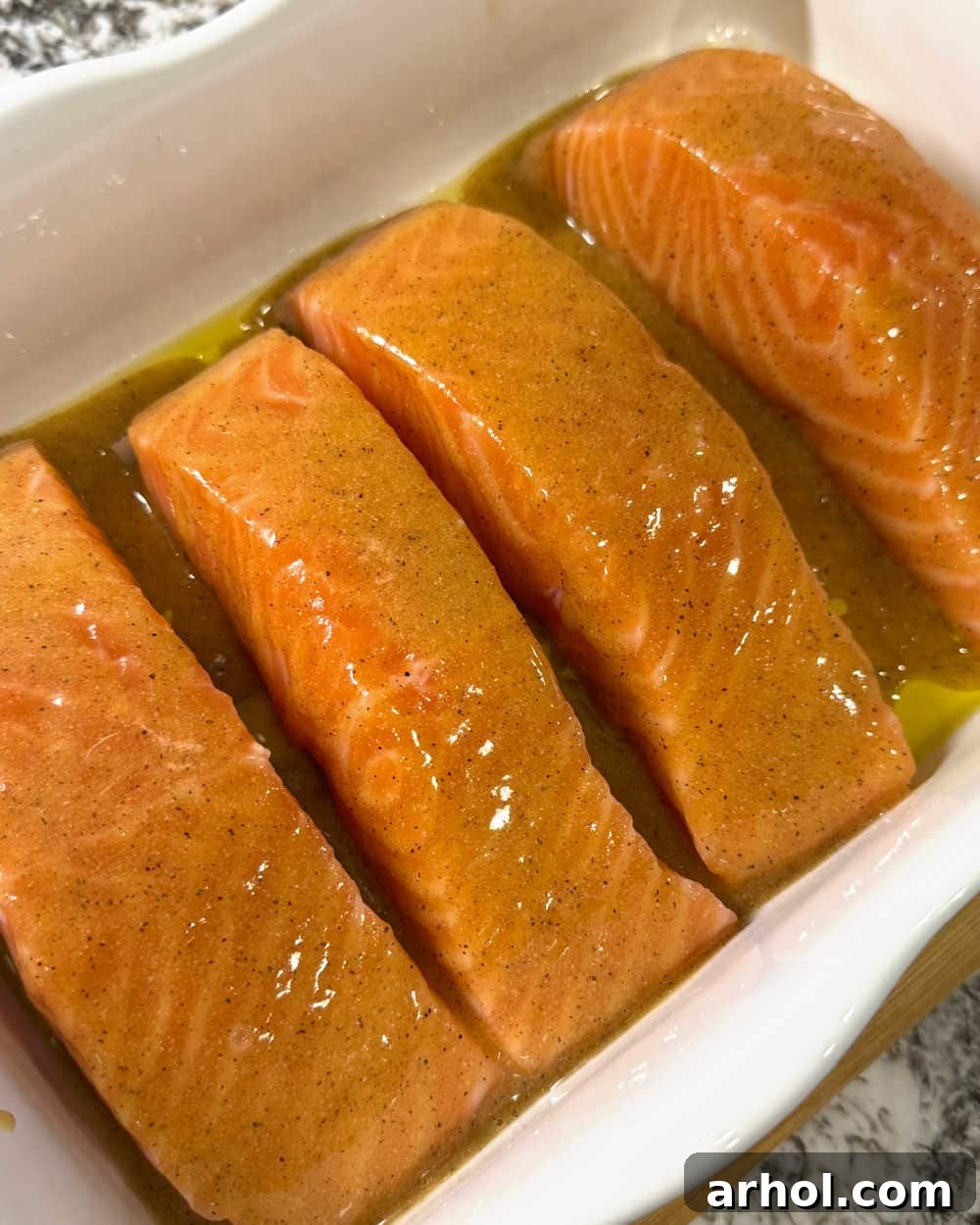 Golden Baked Honey Mustard Salmon 7 salmon fillets with sauce in white dish.