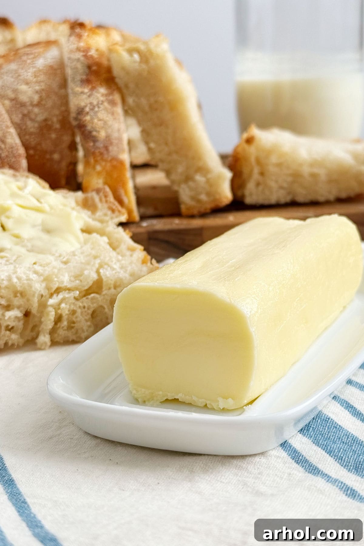 Homemade butter served with fresh homemade bread and a glass of buttermilk on a rustic table.