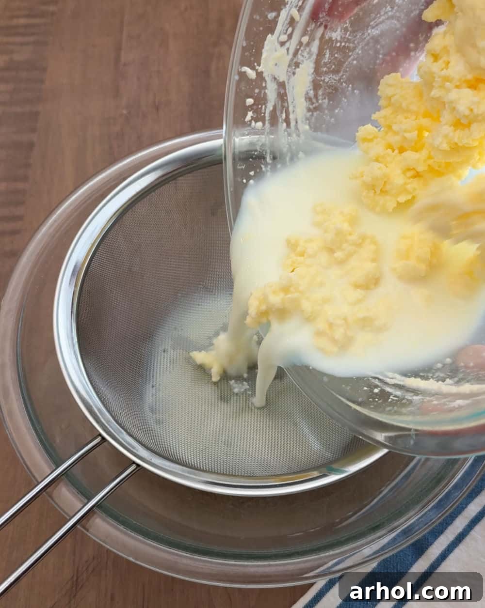 The process of pouring buttermilk and butter solids into a fine mesh strainer over a clean mixing bowl to separate them.