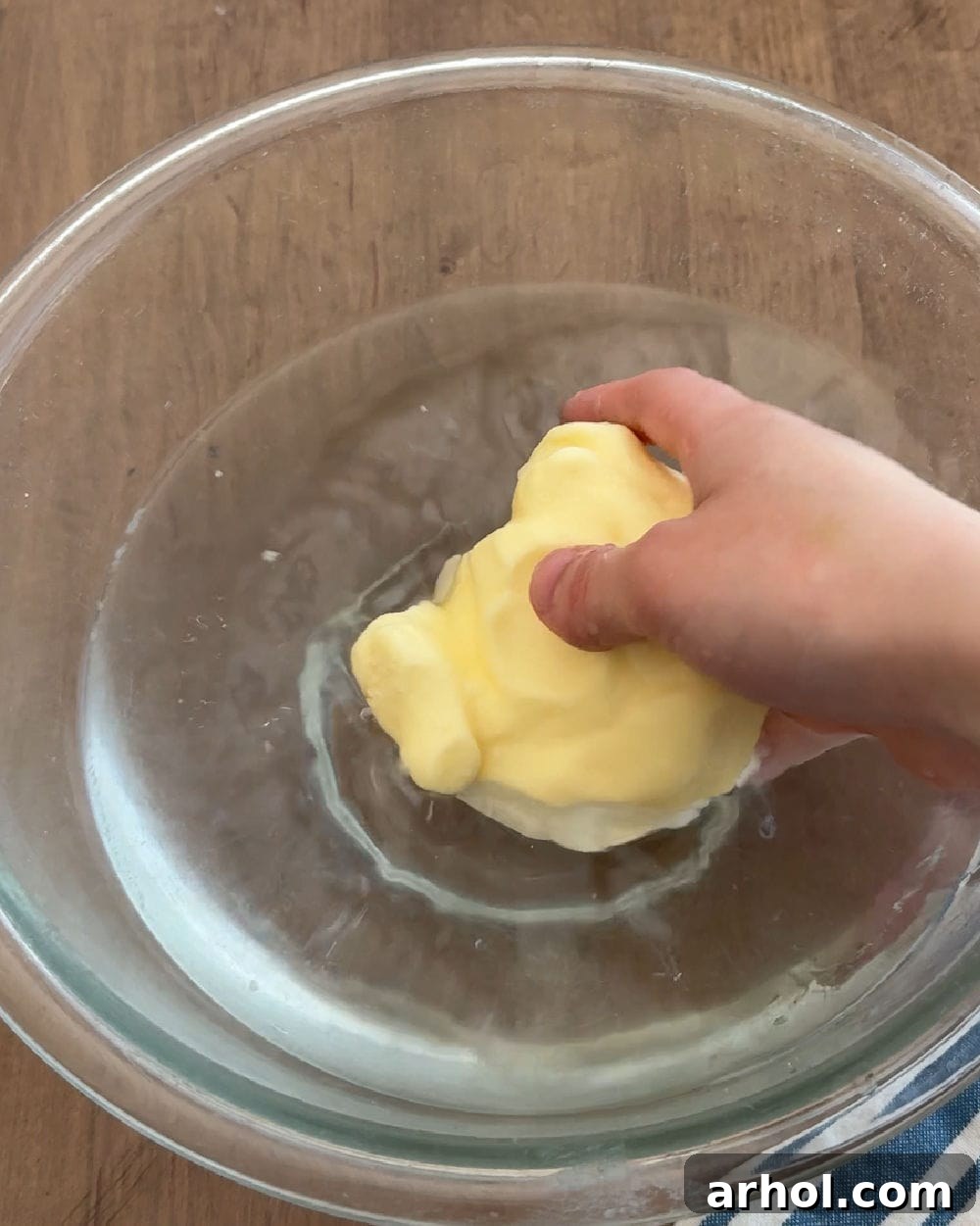 A ball of freshly made butter being rinsed in a bowl of cold water, demonstrating the importance of removing excess buttermilk.