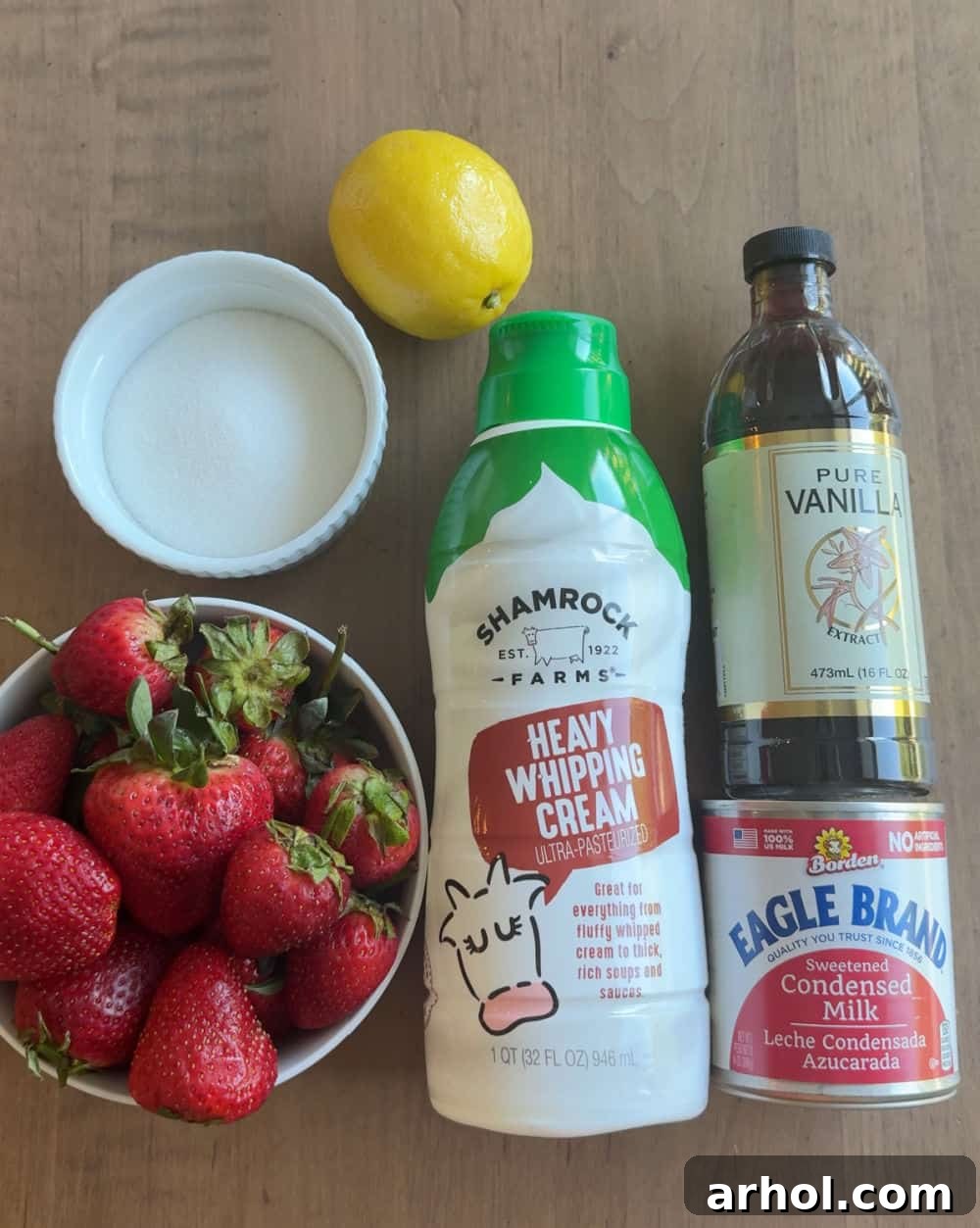 heavy cream, strawberries, sugar, lemon, vanilla, condensed milk on a rustic surface.