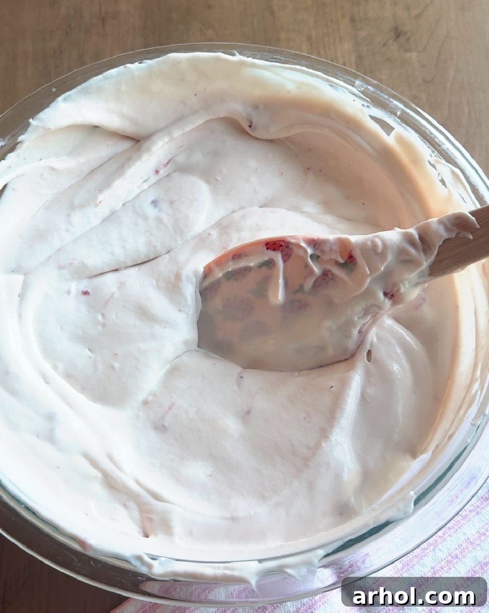 Gently folding whipped cream into the strawberry mixture with a spatula.