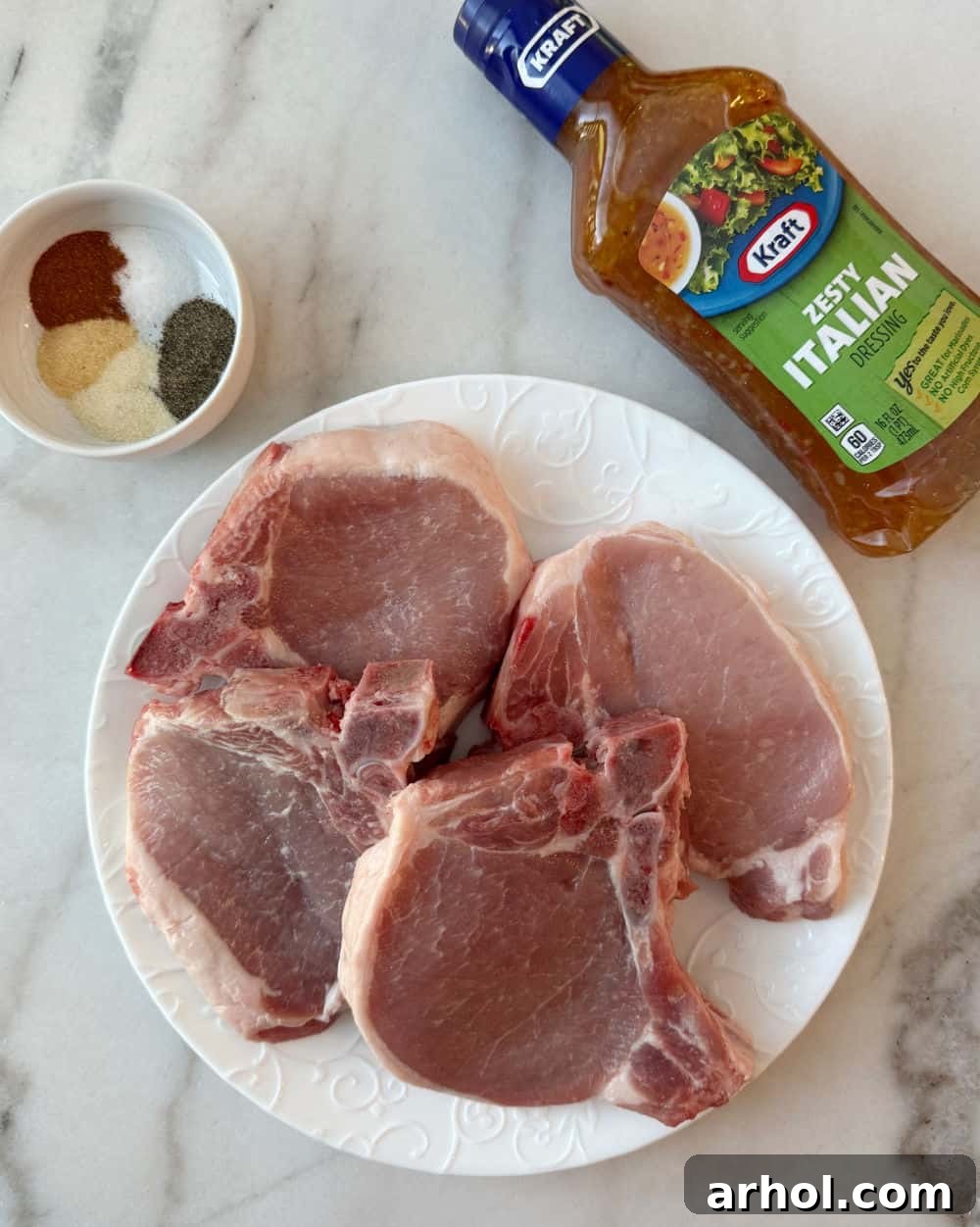 Bone-in pork chops, seasonings, and Italian dressing laid out for recipe.