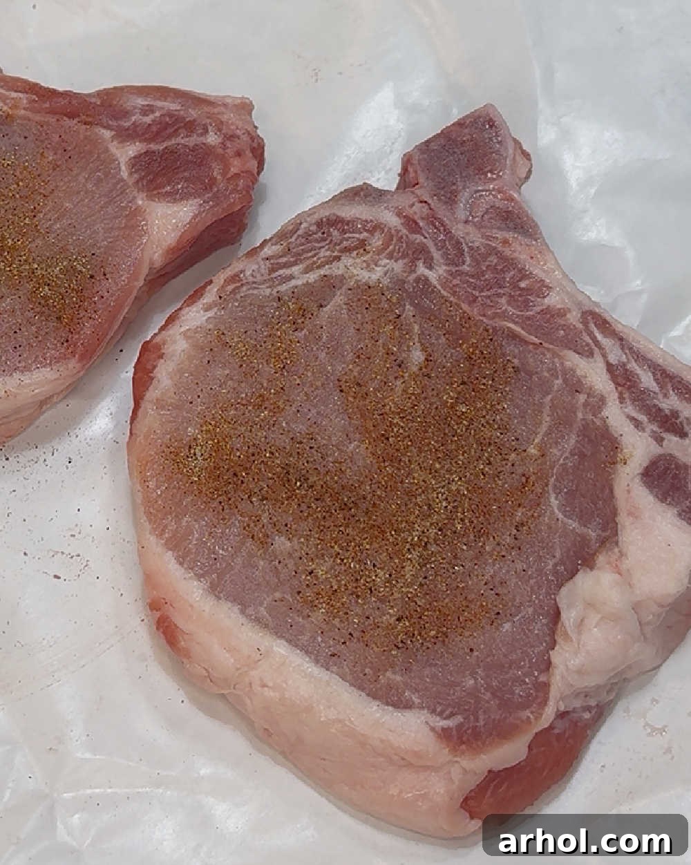 Season pork chops generously with dry rub.