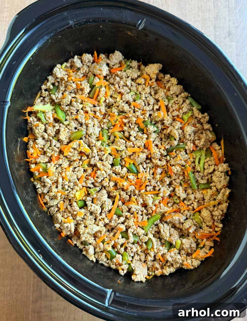 Homemade dog food with ground turkey and various colorful vegetables simmering in a crockpot, ready to be served.