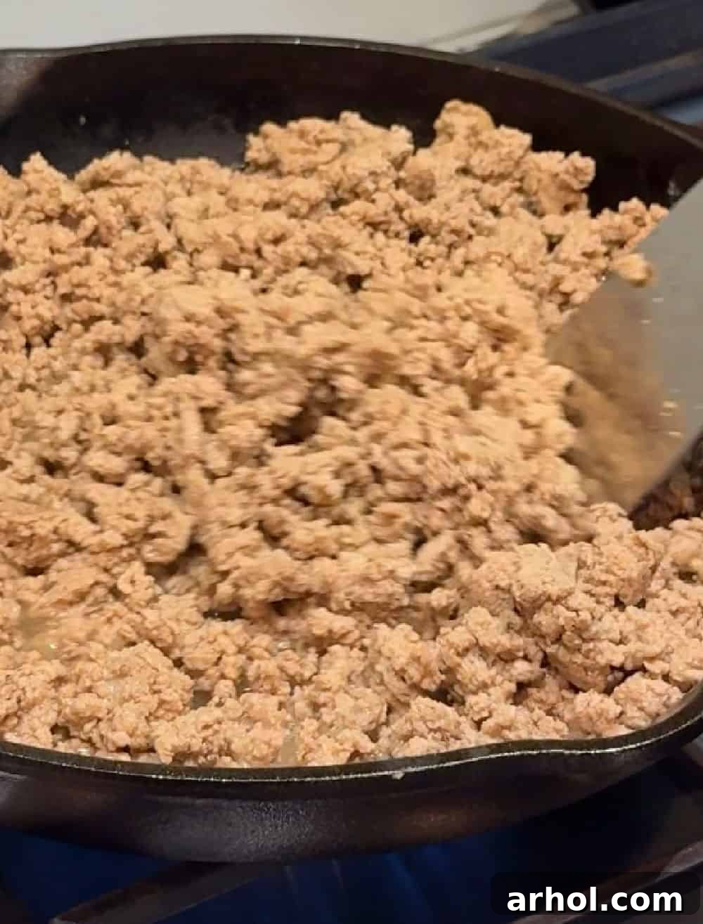 Ground turkey browning in a skillet on the stove.
