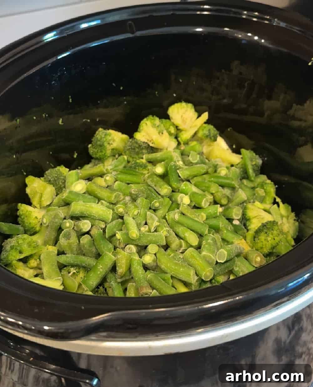 Frozen mixed vegetables placed in the bottom of a slow cooker.